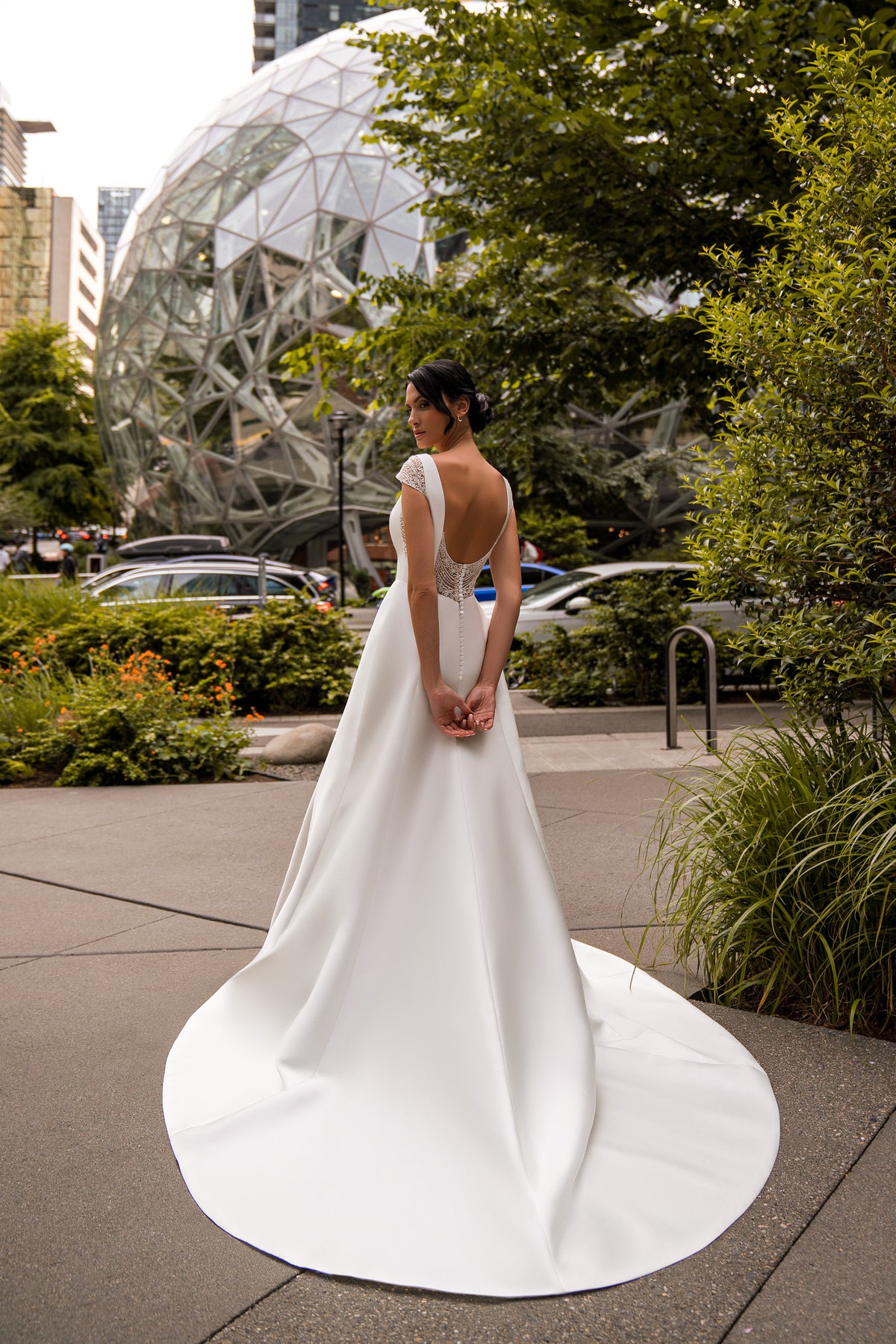 Open V-back and cap sleeves on an ivory A-line wedding dress with a wide sweeping train