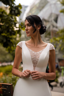 Close-up of beaded lace illusion V-neckline and cap sleeves on an ivory wedding dress