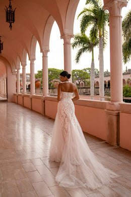 Back view of an ivory lace wedding dress with an open back and sweeping mermaid train