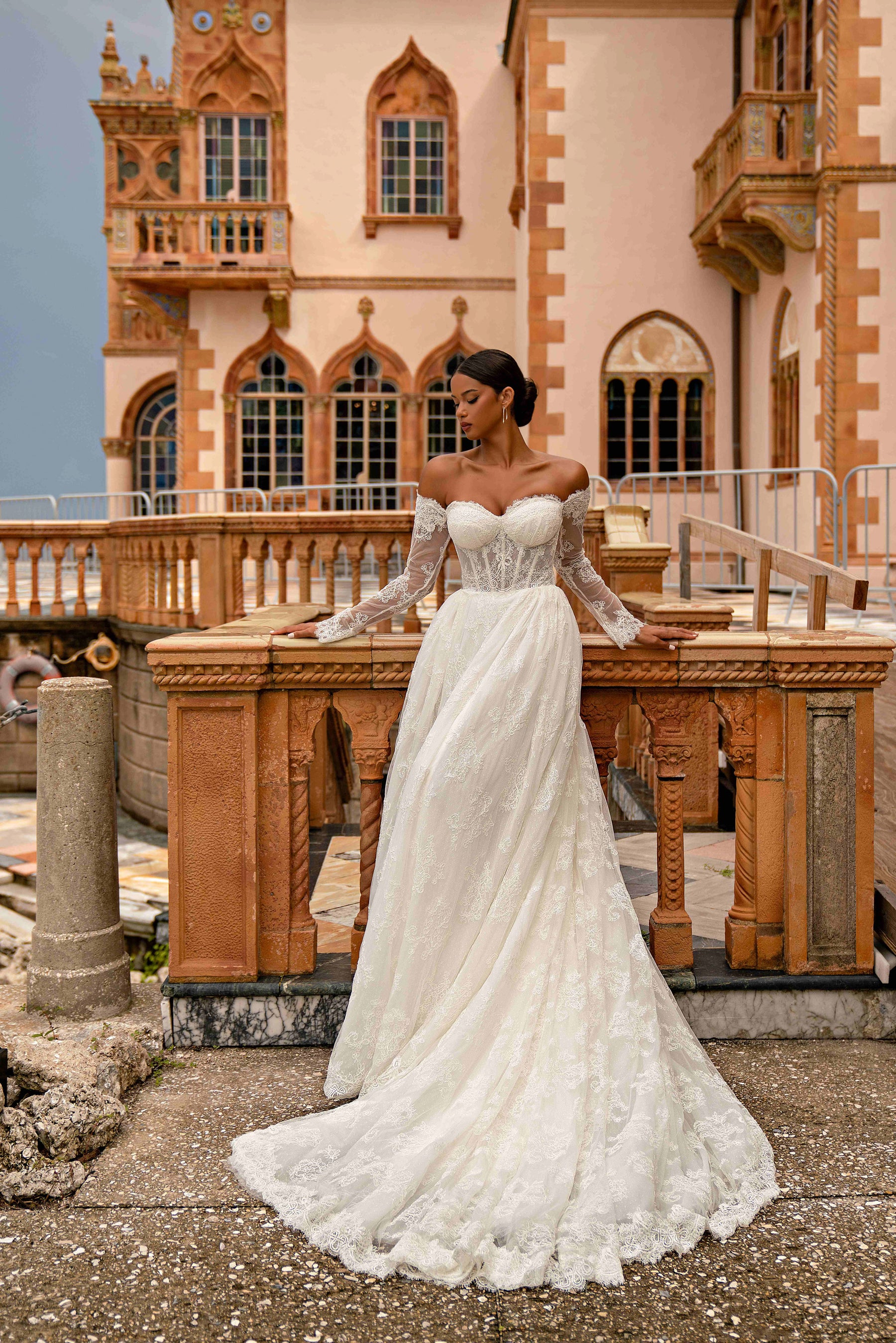 Full-length ivory wedding dress featuring an off-the-shoulder lace bodice, long sleeves, and a train