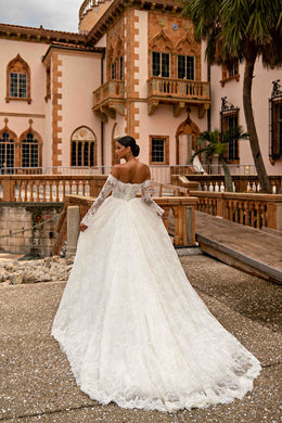 Ivory wedding dress showing a lace-trimmed open back, long sleeves, full A-line skirt, and long train