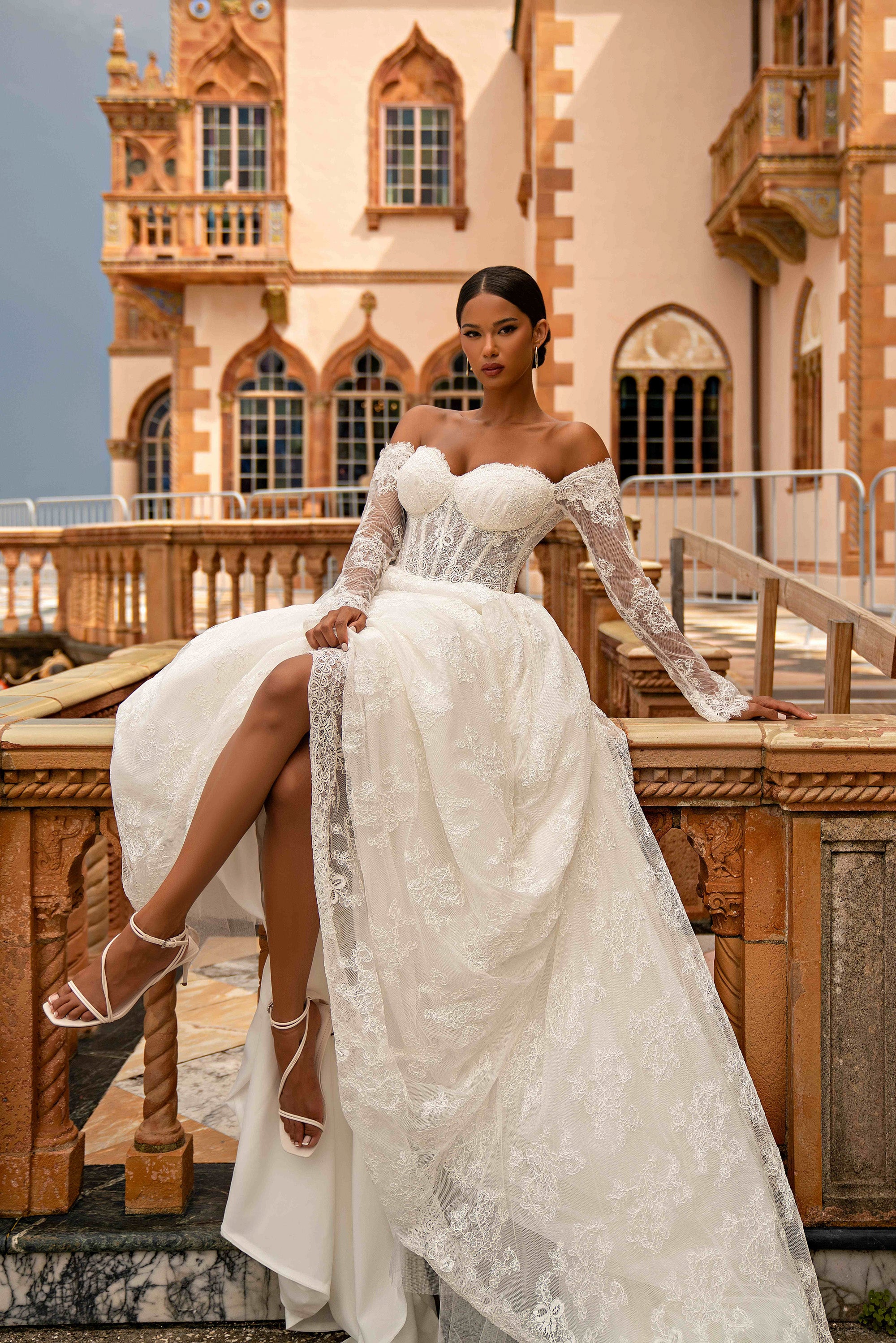 Ivory wedding dress with a thigh-high slit, off-the-shoulder neckline, sheer lace sleeves, and train