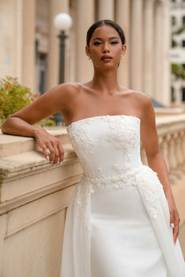 Close-up of a strapless wedding dress with floral lace appliqués and a fitted waist