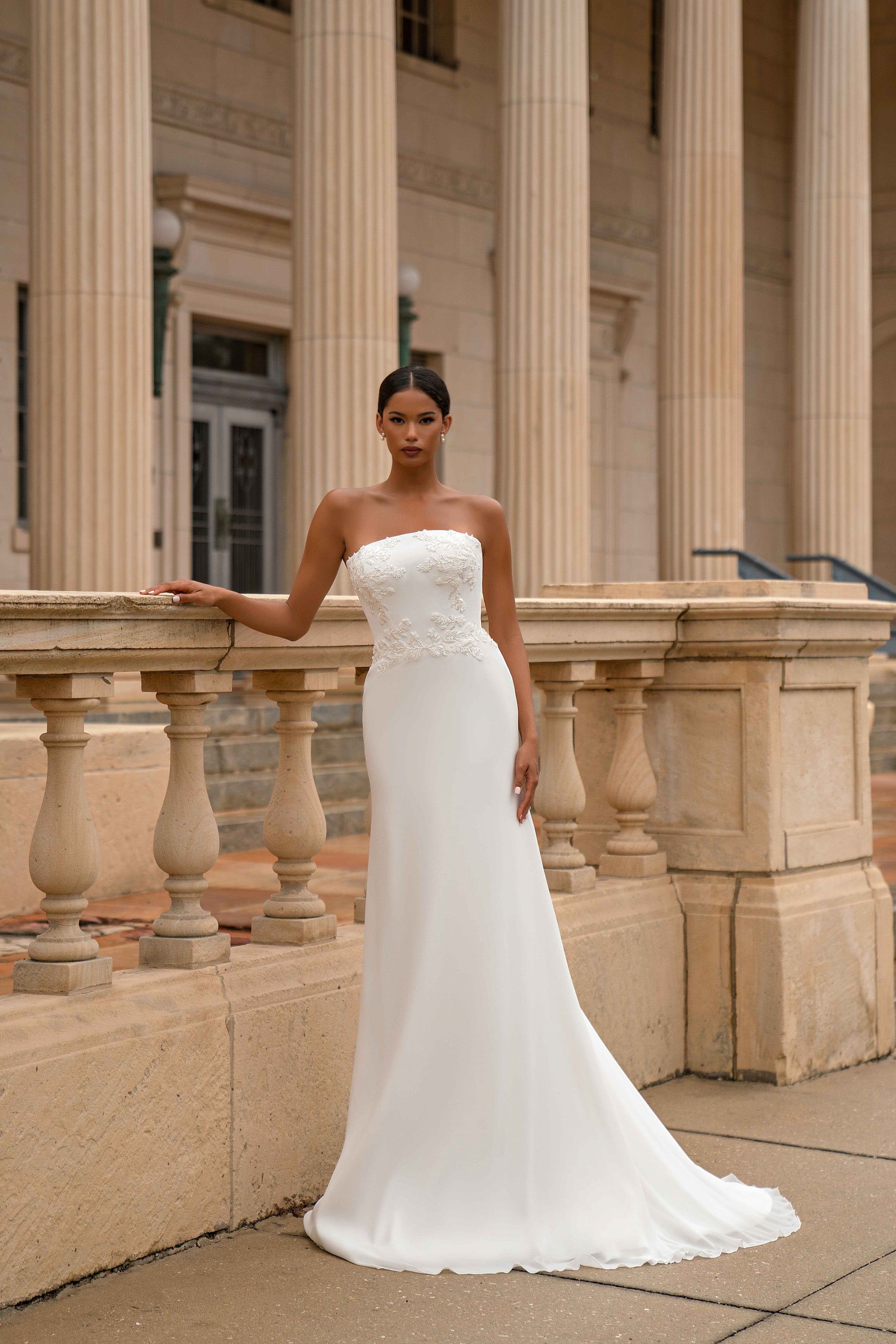 White strapless sheath wedding dress with a lace-embellished bodice and long train