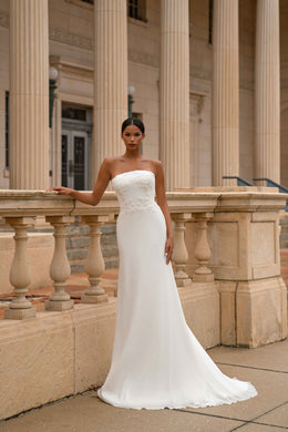 White strapless sheath wedding dress with a lace-embellished bodice and long train