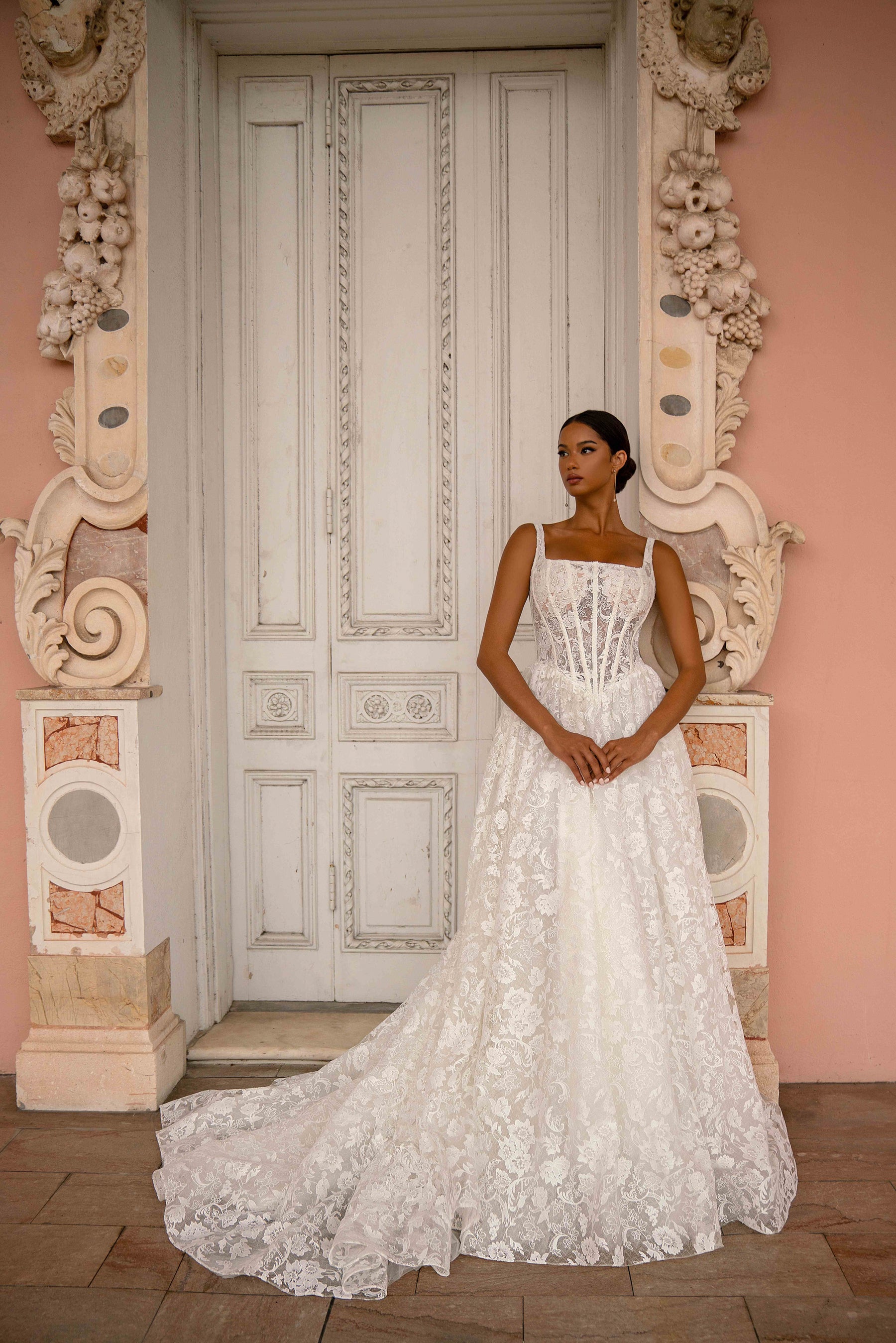 Ivory A-line wedding dress with a square neckline, corset-style bodice, floral lace, and a sweeping train