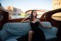 Black evening dress with a structured sweetheart bodice, embellished shoulders, and a flowing skirt