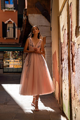 Blush pink evening dress with a V-neckline, sleeveless bodice, floral beadwork, and flowing tulle skirt