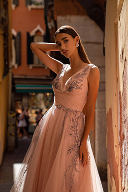 Blush pink evening dress featuring a deep V-neckline and ornate floral beadwork across the bodice and skirt