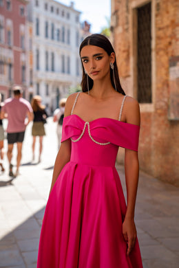 Bright fuchsia evening dress with an off-the-shoulder neckline, thin straps, chain trim, and a pleated full skirt