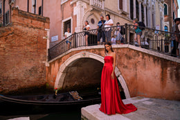 Red strapless evening dress with a ruched bodice, long pleated skirt, and trailing hem