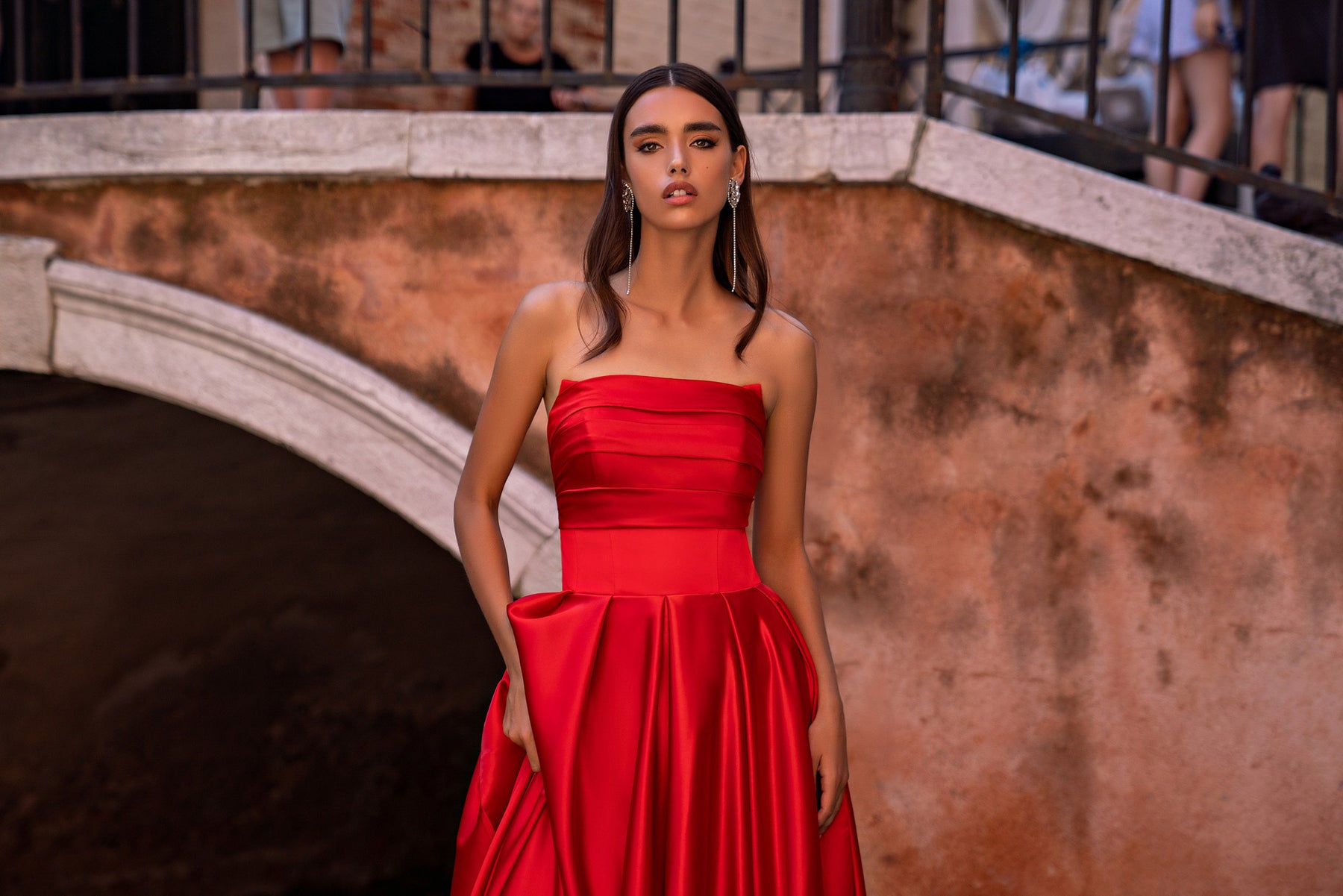 Close view of a red strapless evening dress with layered ruching and a gathered full skirt