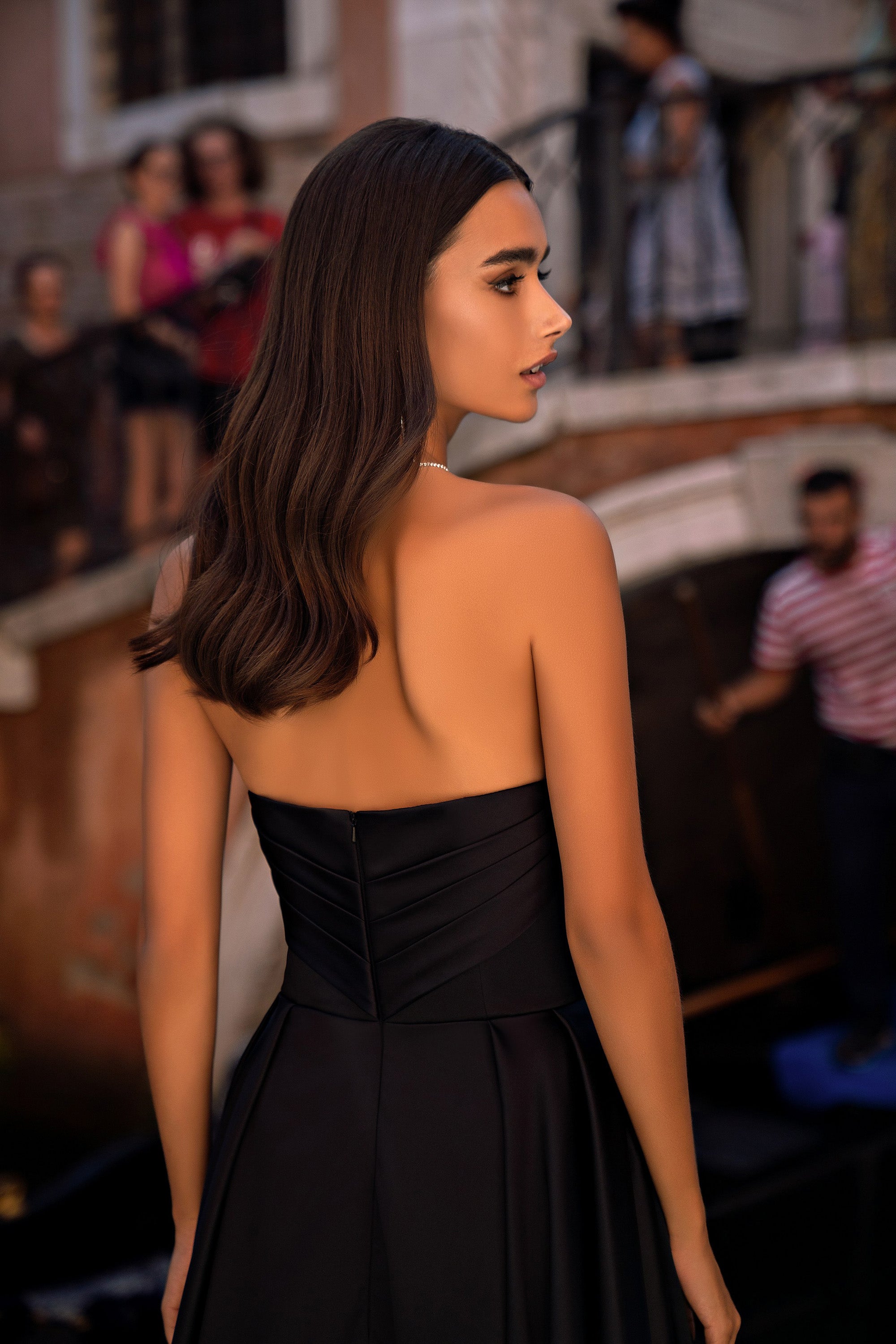 Black strapless evening dress showing a structured back with horizontal seams and a full skirt