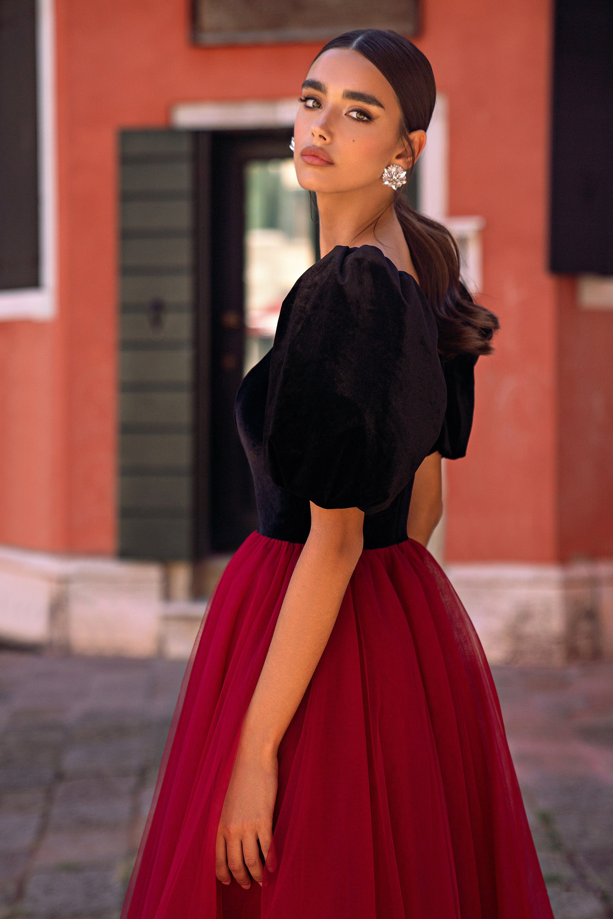 Side view of a black bodice with puff sleeves and a full red skirt on an evening dress
