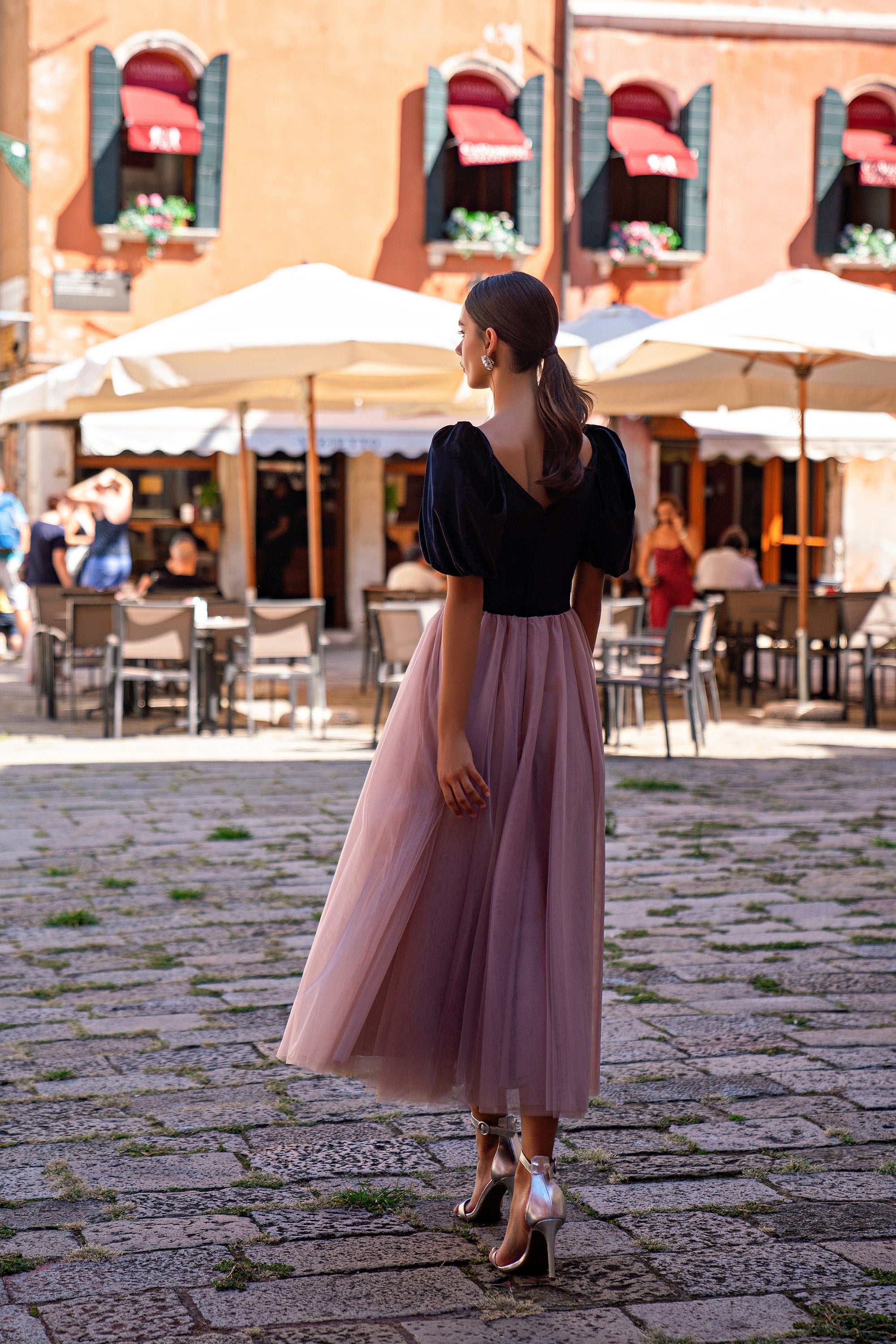 Back view of a black evening dress with puff sleeves, a V-shaped back, and a mauve full skirt