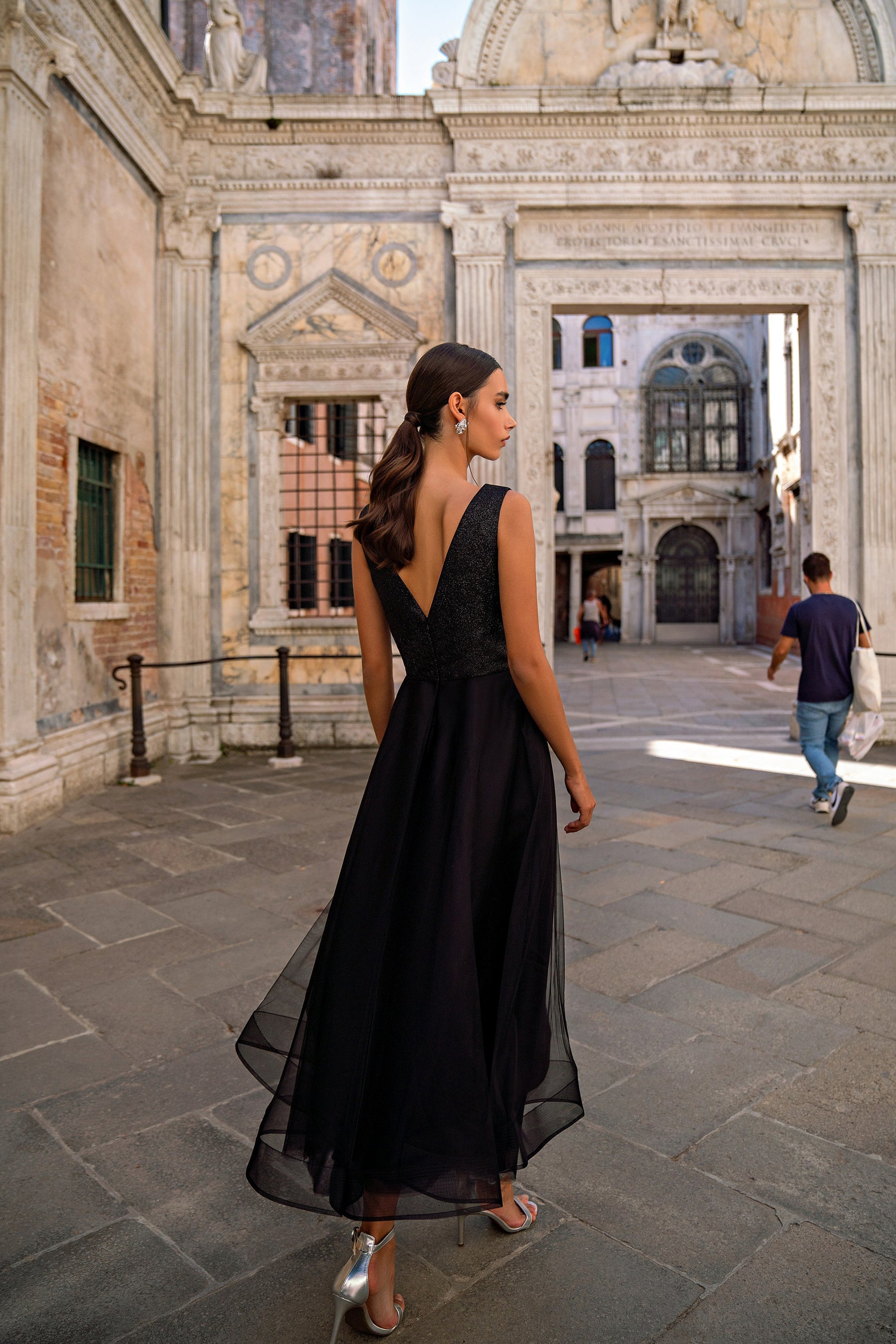 Deep V-back and flowing sheer-overlay skirt on a black sleeveless evening dress