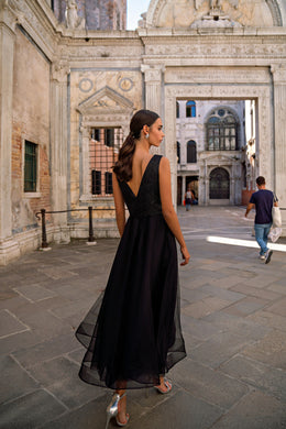 Deep V-back and flowing sheer-overlay skirt on a black sleeveless evening dress