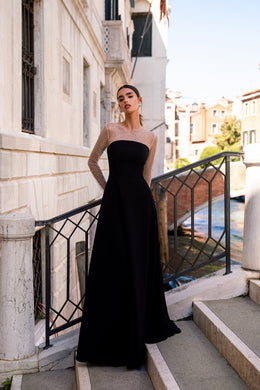 Black floor-length evening dress with a strapless bodice and sheer, crystal-embellished long sleeves