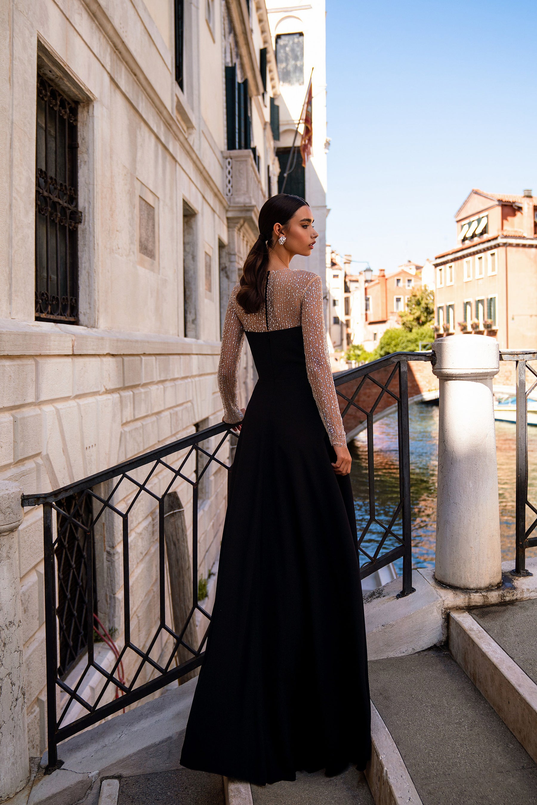 Black evening dress with a full-length skirt and a sheer, rhinestone-embellished back and sleeves
