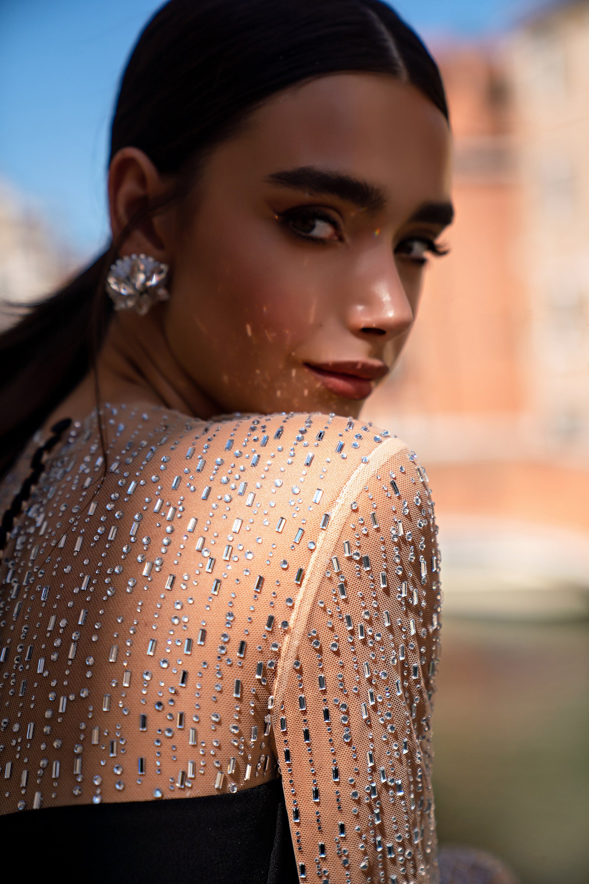 Close-up of the sheer beaded back and sleeve detailing on a black evening dress