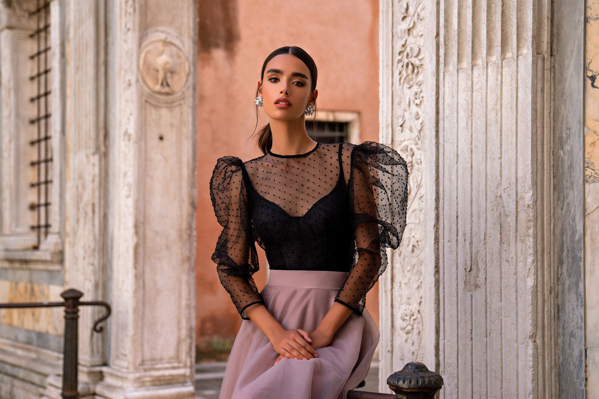 Close-up of an evening dress with a dotted sheer neckline, puff sleeves, and black fitted bodice