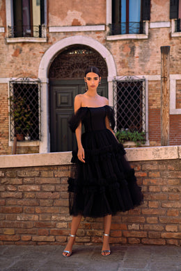 Black evening dress with an off-the-shoulder neckline, sheer puff sleeves, and a tiered ruffle skirt