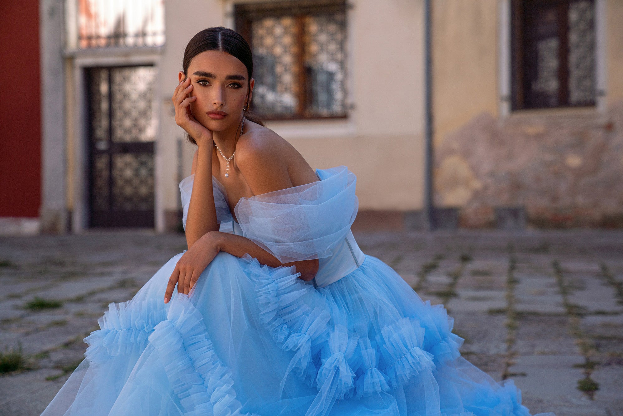 Light blue evening dress featuring voluminous sheer sleeves and cascading ruffles across the full skirt