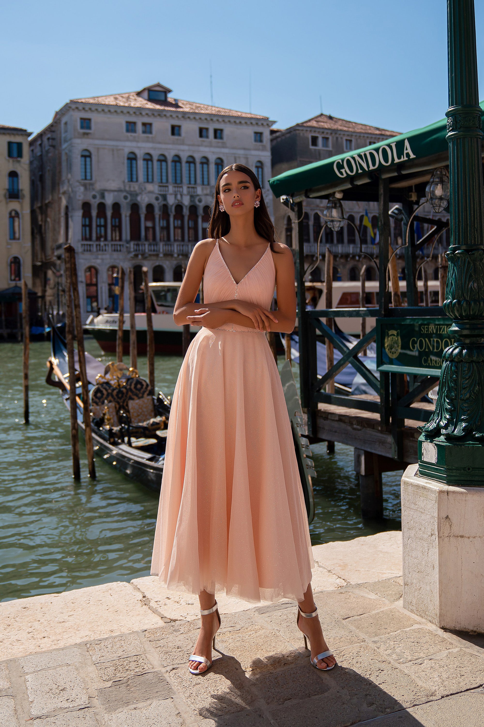 Peach evening dress with thin straps, a V-neckline, sparkling texture, and flowing A-line skirt