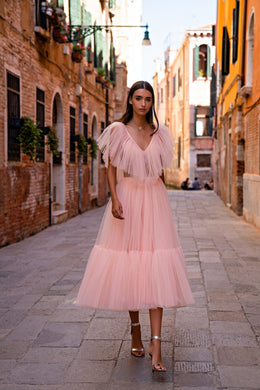 Pink evening dress with a deep V-neckline, layered sheer flutter sleeves, and a tiered pleated skirt