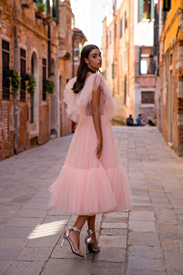 Side-back view of a pink evening dress with sheer flutter sleeves, fitted waist, and tiered tulle skirt