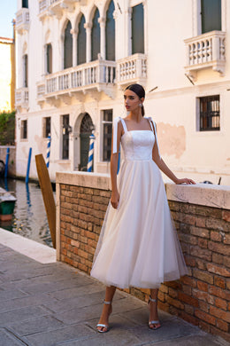 Ivory evening dress with a sparkling square-neck bodice, tied shoulder straps, and flowing tulle midi skirt