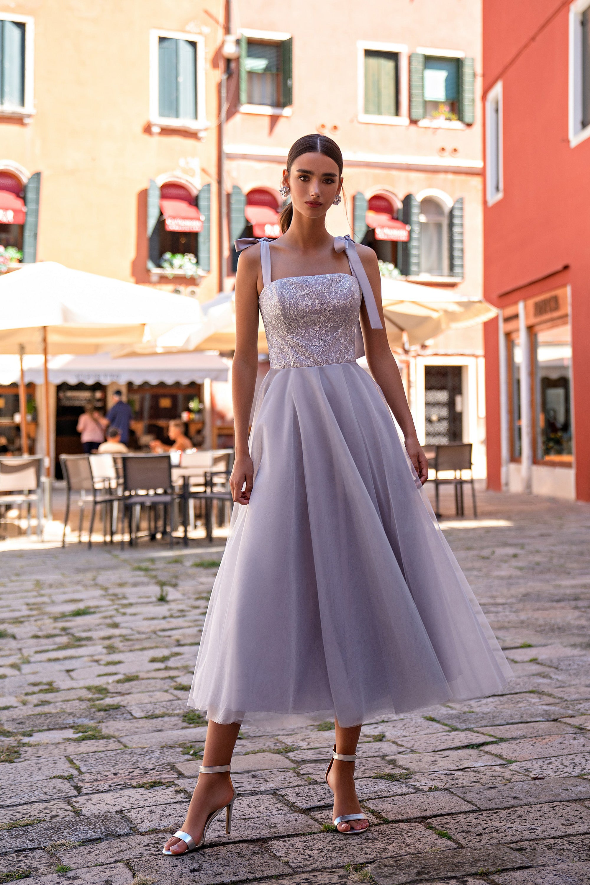 Ivory evening dress with a fitted sequin bodice, square neckline, ribbon straps, and flowing midi skirt