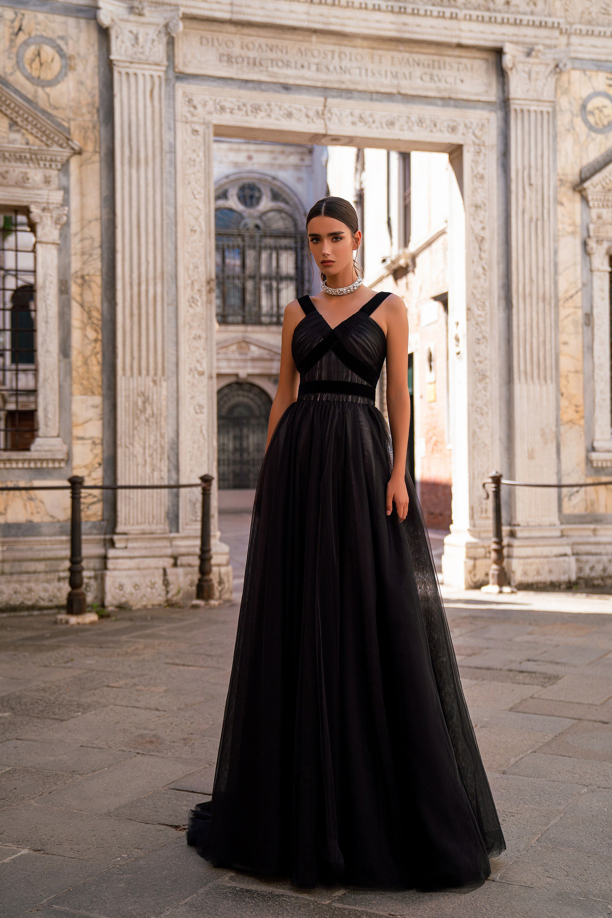 Black evening dress with wide shoulder straps, a crisscross bodice, and a flowing floor-length skirt
