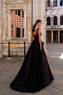 Black evening dress showing a low open back, wide straps, and a sweeping floor-length skirt