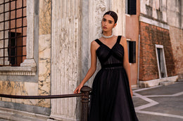 Black evening dress with a structured crisscross bodice, wide straps, and a full flowing skirt