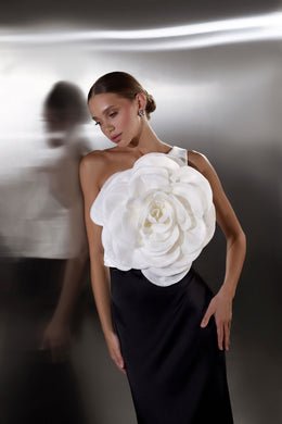 Black evening dress with a fitted silhouette, one-shoulder styling, and an oversized white floral bodice appliqué