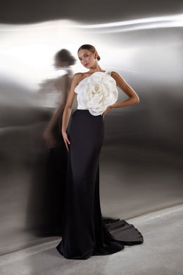Floor-length black evening dress with an oversized white flower bodice and a dramatic pooling train
