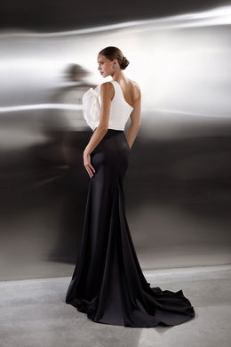 Open-back black evening dress with a white floral bodice accent, fitted skirt, and sweeping train