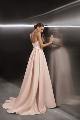 Blush pink evening dress with a low open back, thin straps, full sweeping skirt, and floor-length train