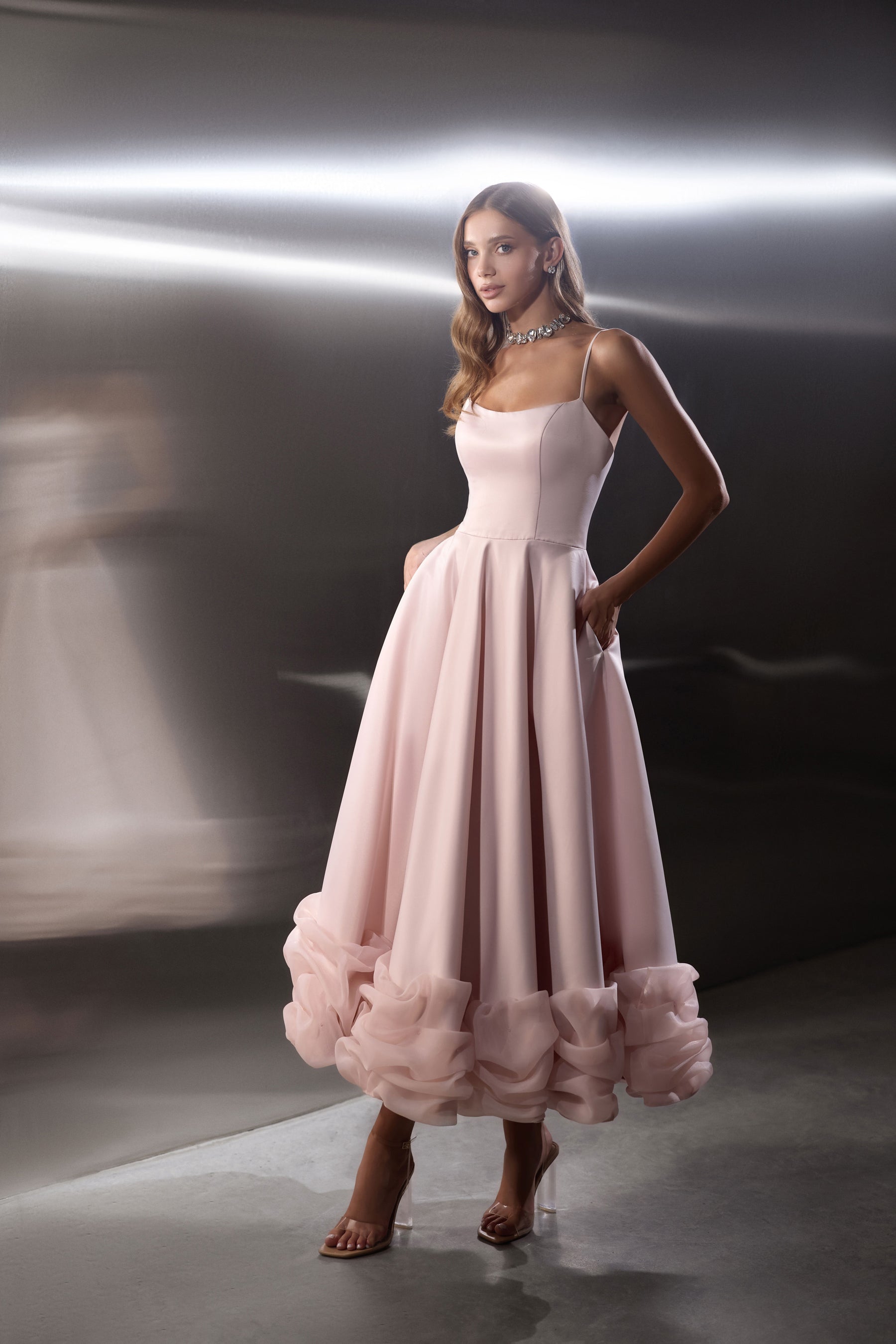 Blush pink evening dress with a square neckline, fitted bodice, full skirt, and ruffled hem