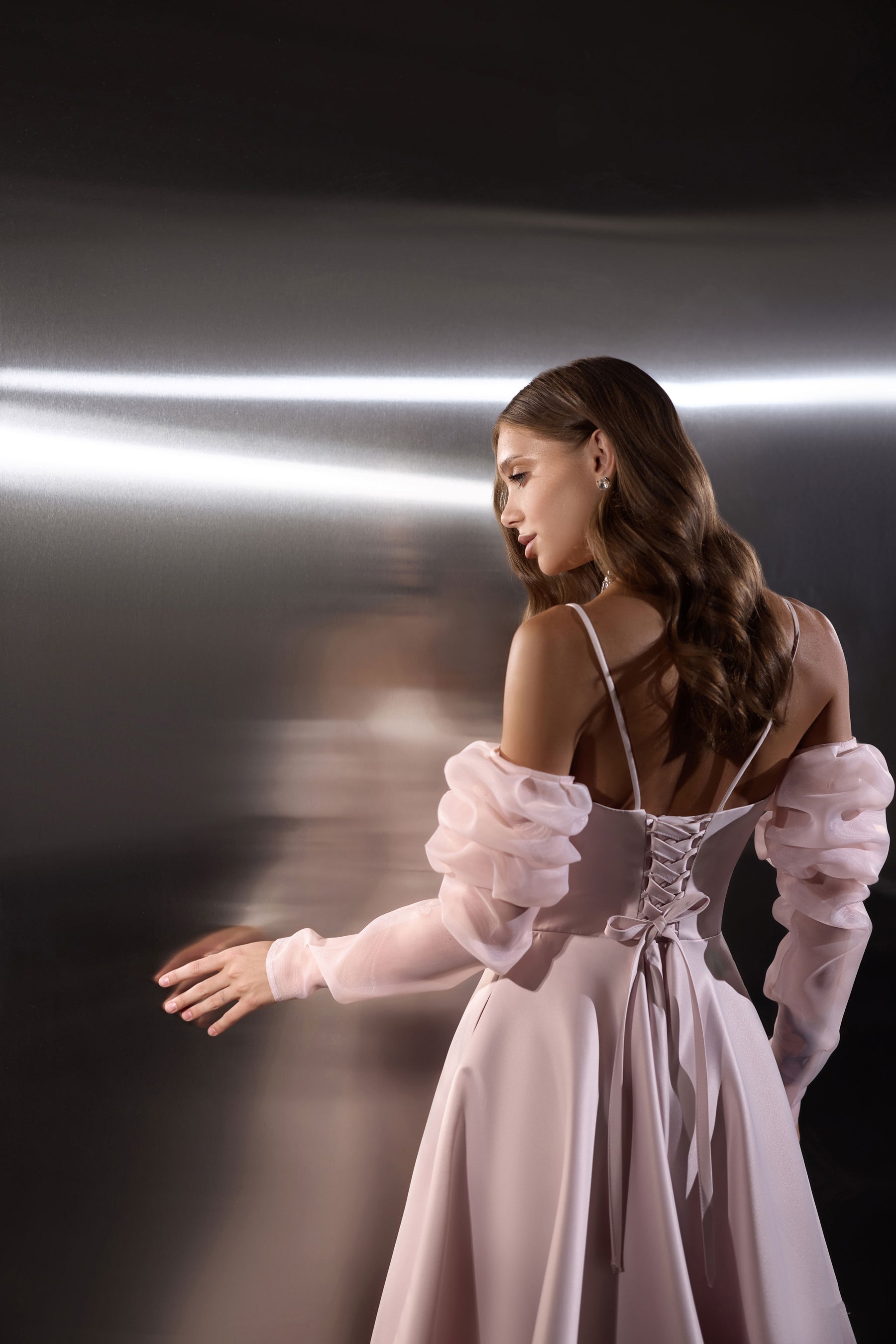 Lace-up corset back on a blush pink evening dress with thin straps and sheer puff sleeves