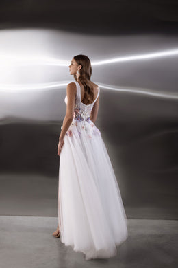 White evening dress showing a low rounded back, floral embroidery at the waist, and a long flowing tulle skirt