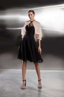 Black evening dress with a full midi skirt, cutout neckline, and sheer blush puff-sleeve capelet