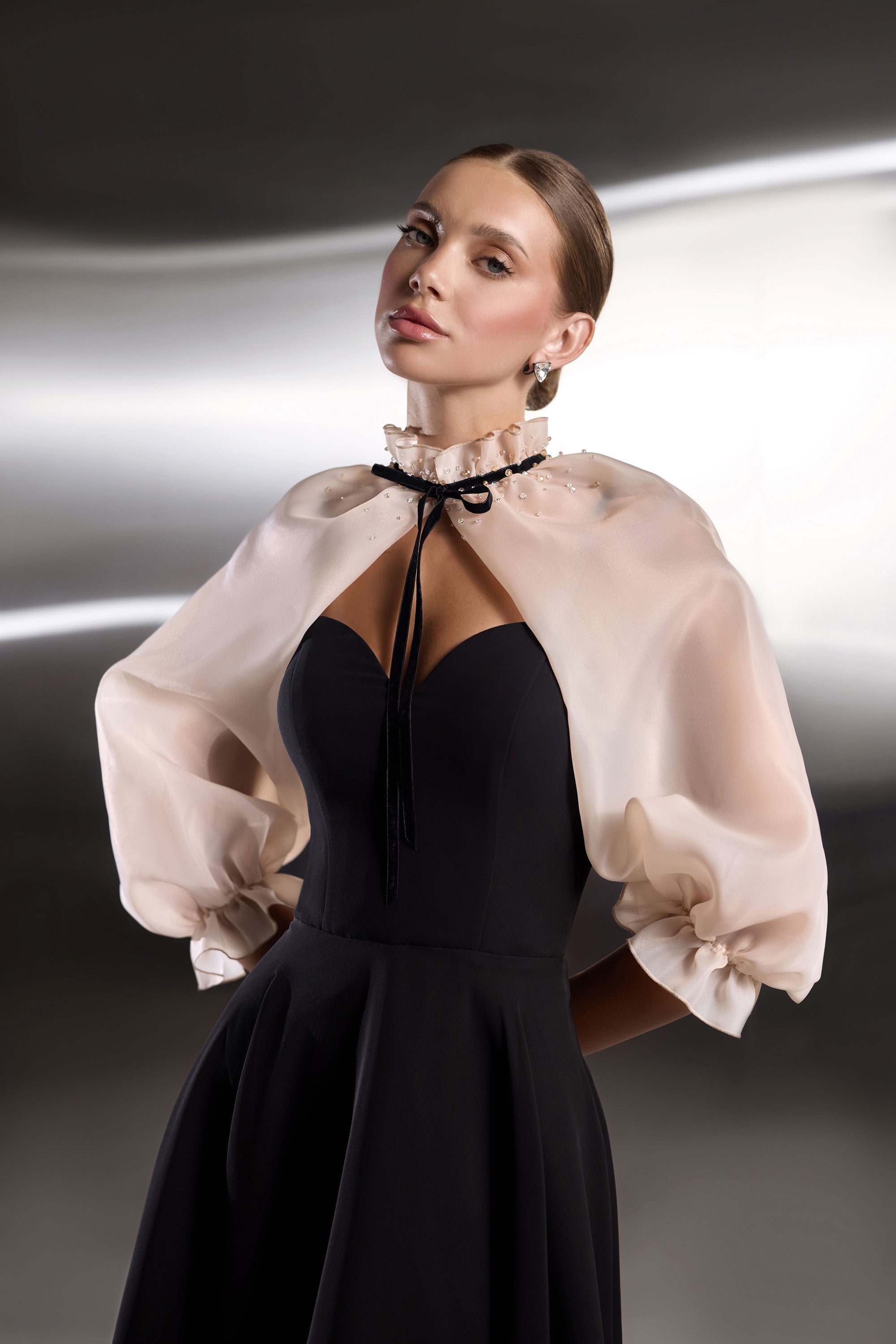 Black evening dress featuring a sweetheart bodice, deep center cutout, and sheer blush puff sleeves with ruffled cuffs