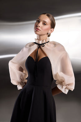 Black evening dress featuring a sweetheart bodice, deep center cutout, and sheer blush puff sleeves with ruffled cuffs