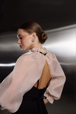 Open-back black evening dress with waist ties and a sheer blush capelet with a high gathered collar
