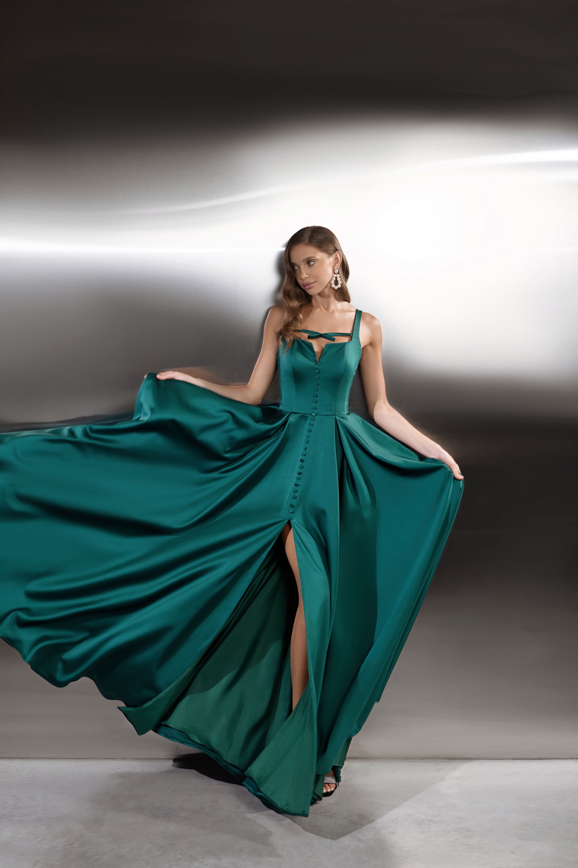 Emerald green evening dress with corset-style bodice, thin straps, front buttons, and thigh-high slit