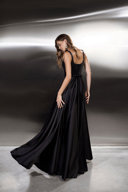Back view of a black evening dress with a low back, corset-style lacing, and long flowing train