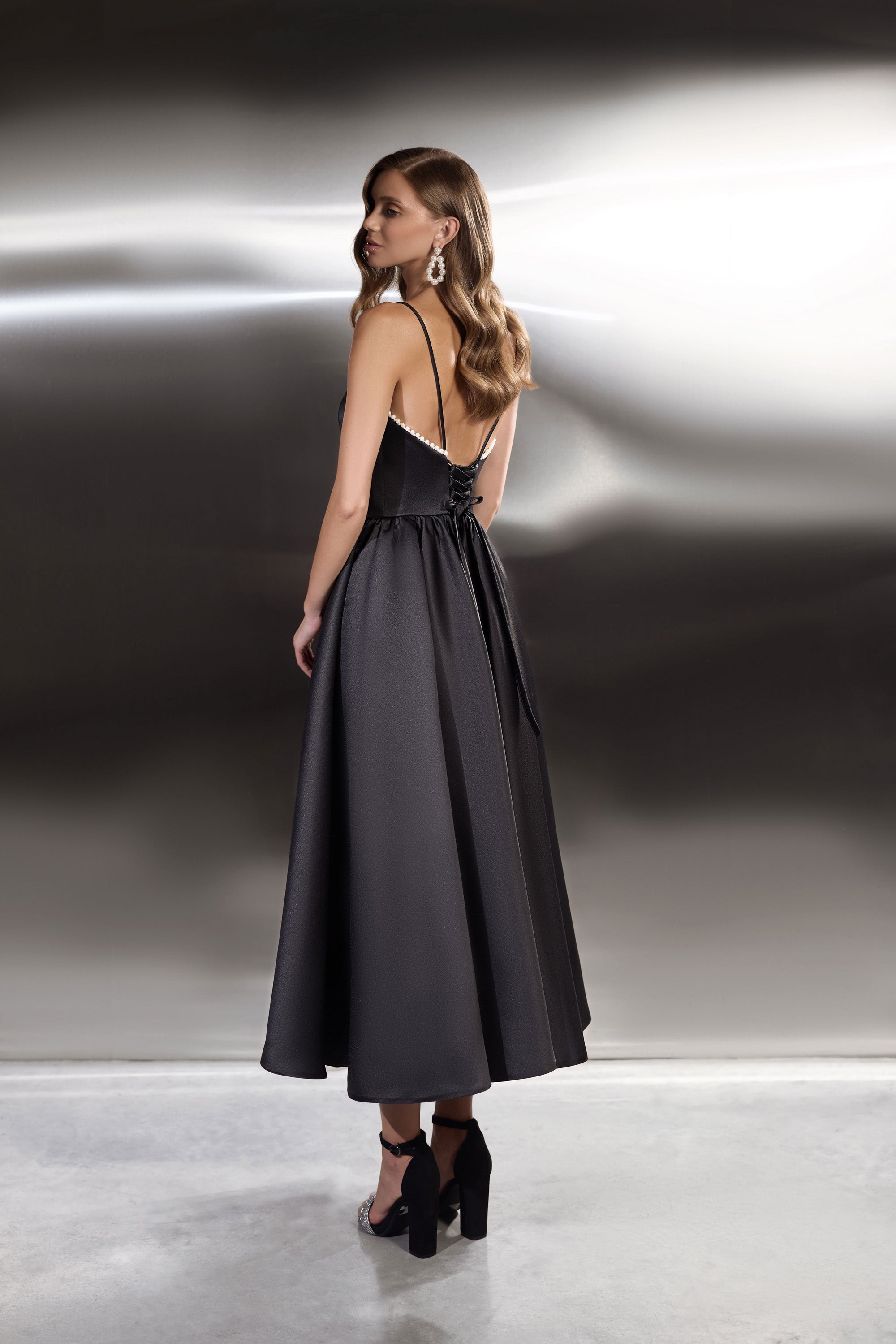 Black evening dress with thin straps, a low open back edged in beads, and a flowing full skirt