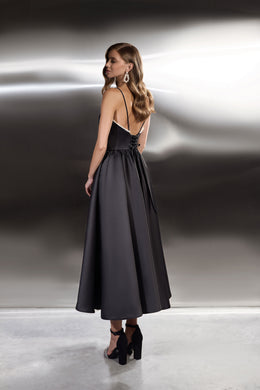 Black evening dress with thin straps, a low open back edged in beads, and a flowing full skirt
